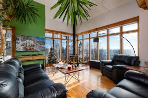 a living room with black leather furniture and large windows at Havre sur la Baie in Baie-Saint-Paul
