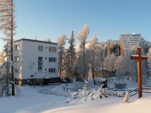 a cross in the snow in front of a building at Vila Emma in Štrbské Pleso