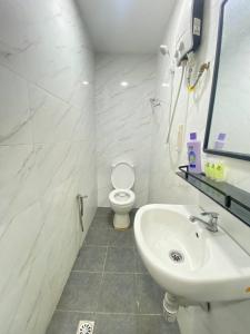 a white bathroom with a toilet and a sink at Enviropath Hotel now Bayan Nur Inn in Kampong Pengkalan