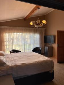 a bedroom with a bed and chairs and a window at Swakhanya Haus in Vereeniging