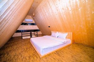 a bed in a room with a wooden wall at Raj Villas by Jomotel - A Riverside Retreat in Banjār