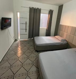 a room with two beds and a tv in it at Studios Mattigor - ao lado da Dutra em Caçapava-SP in Caçapava