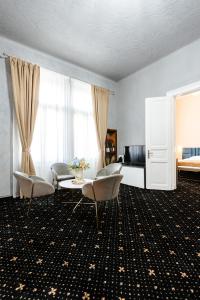 a living room with chairs and a table and a bed at Palazzo Bellariva Dimora in Cluj-Napoca