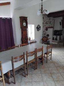 a dining room with a table and a grandfather clock at Maison de caractère in Saint-Vert