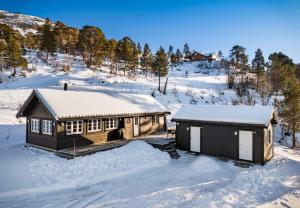 a log cabin in the snow with snow at Panoramic View of Voss - Private Cabin & Patio in Vossevangen