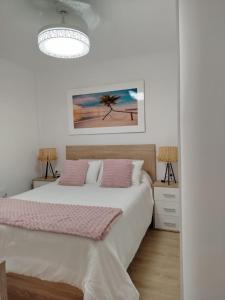 a white bedroom with a bed with pink pillows at Rosa de la Sal in La Mata +13 photos