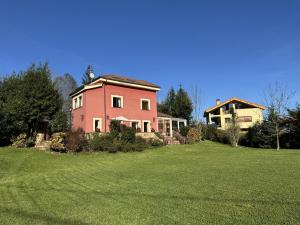 a large pink house on a grass field at Casa Los Campones en Asturias VV-3585-AS in Nava