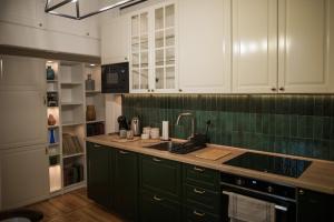 a kitchen with green and white cabinets and a sink at Apartament Wspomnień in Zamość +25 photos