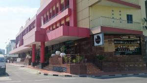 a large pink building with a store on a street at Hotel & Apartment Ambassador 3 in Labuan