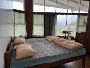 a bedroom with a bed with pillows and a window at Baguio BELL Staycation in Baguio