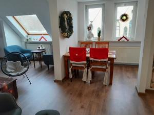 a dining room with a table and red chairs at Ferienwohnung Auszeit in Aue