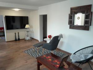 a living room with a tv and a chair and a table at Ferienwohnung Auszeit in Aue