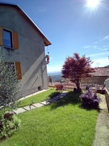 a house with a grassy yard next to a building at La piazzetta del sole in Pettinengo