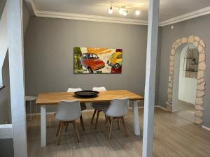 a dining room table with chairs and a painting on the wall at Murgtalhouse Ferienwohnungen in Murg