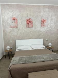 ein Schlafzimmer mit einem Bett und vier Rosen an der Wand in der Unterkunft S'Istella Affittacamere in Tinnura