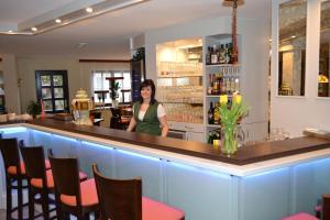 a woman standing behind a bar in a restaurant at Ammerscher Bahnhof in Mühlhausen