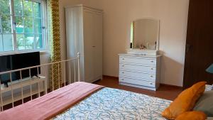 a bedroom with a bed and a dresser with a mirror at The Lemon Tree House in Quinta do Conde