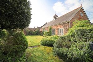 an old brick building with a grass yard in front of it at Beautiful Cottage & Garden Quantock Hills in Nether Stowey
