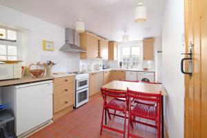 a kitchen with two red chairs at a counter at Beautiful Cottage & Garden Quantock Hills in Nether Stowey