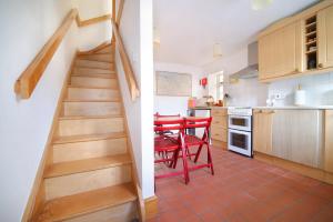 a kitchen with a staircase and a red table and chairs at Beautiful Cottage & Garden Quantock Hills in Nether Stowey