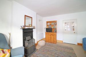 a living room with a fireplace and a blue couch at Beautiful Cottage & Garden Quantock Hills in Nether Stowey +15 photos