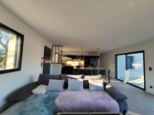 a living room with a large couch and a kitchen at L'Etape de Charme in Bourdeaux