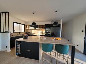 a kitchen with a large island with two blue bar stools at L'Etape de Charme in Bourdeaux