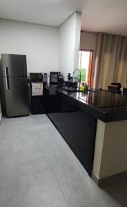 a kitchen with a black counter and a refrigerator at Refugio Vem Viver in Mairiporã +14 photos