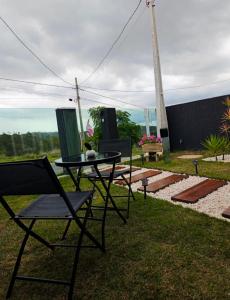 a patio with a table and chairs in the grass at Refugio Vem Viver in Mairiporã