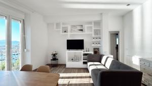 a white living room with a couch and a tv at EDIFICI ROSA- Ático primera línea in Port de la Selva