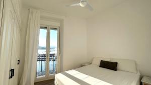 a white bedroom with a bed and a window at EDIFICI ROSA- Ático primera línea in Port de la Selva