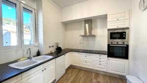 a kitchen with white cabinets and a sink and a window at EDIFICI ROSA- Ático primera línea in Port de la Selva