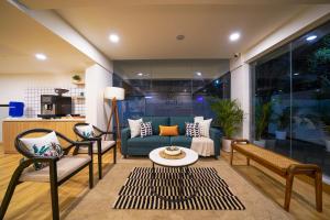 a living room with a blue couch and two chairs at Olive Hotel Baner by Embassy Group in Pune