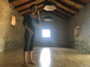 Una mujer parada en una habitación con una luz. en Vale, en Vale