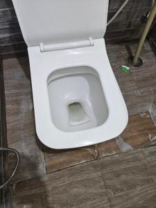 a white toilet in a bathroom with a floor at Rove Haven Condo in Bangalore +8 photos