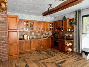a kitchen with wooden cabinets and a brick wall at Cabana Bradul Adelinei in Bucsin