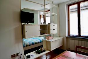 a room with a shelf with a tv and a table at Dany's house in Lecco