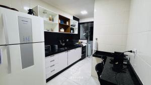 a kitchen with white cabinets and a black and white refrigerator at Apartamento Centro Ubatuba - Ubatuba House Temporada in Ubatuba