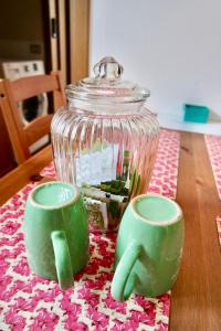a glass jar and two green cups on a table at Dany's house in Lecco