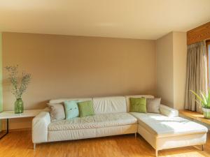 a living room with a white couch with green pillows at Apartment Chesa Tscheppa 1 by Interhome in Sils Maria