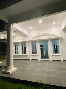 a white house with a pillar and windows at Laura villa in Cisarua