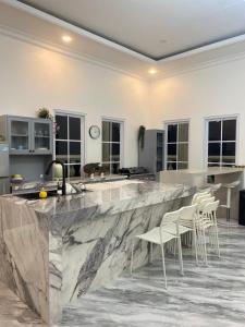 a kitchen with a large marble counter with white chairs at Laura villa in Cisarua