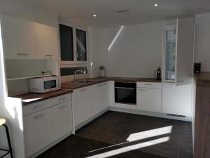 a kitchen with white cabinets and a microwave at Apartment HIRSCHEN by Interhome in Gossau