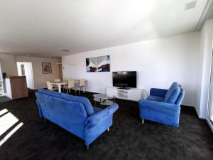 a living room with two blue chairs and a tv at Apartment HIRSCHEN by Interhome in Gossau