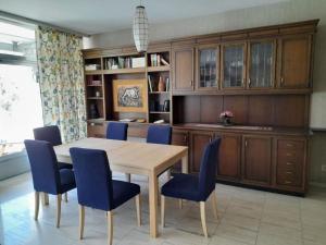 a dining room with a wooden table and blue chairs at Apartment Pavillon Castagneto by Interhome in Castasegna