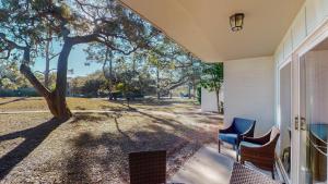 a porch with two chairs and a tree at Atlantic Breeze #4 in Jekyll Island