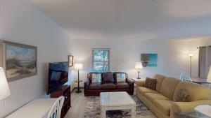 a living room with a couch and a tv at Atlantic Breeze #4 in Jekyll Island