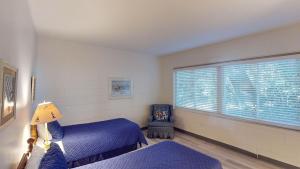 a bedroom with two beds and a window with a chair at Atlantic Breeze #4 in Jekyll Island