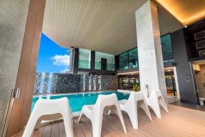 an indoor pool with white chairs and a house at Pause and Play Hotel in Chiang Mai