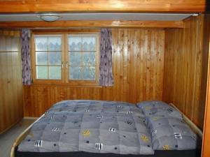 a bed in a bedroom with a wooden wall at Apartment Gubel by Interhome in Alt Sankt Johann